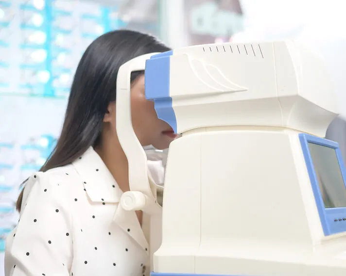 Patient resting her chin on an automated eye-testing instrument