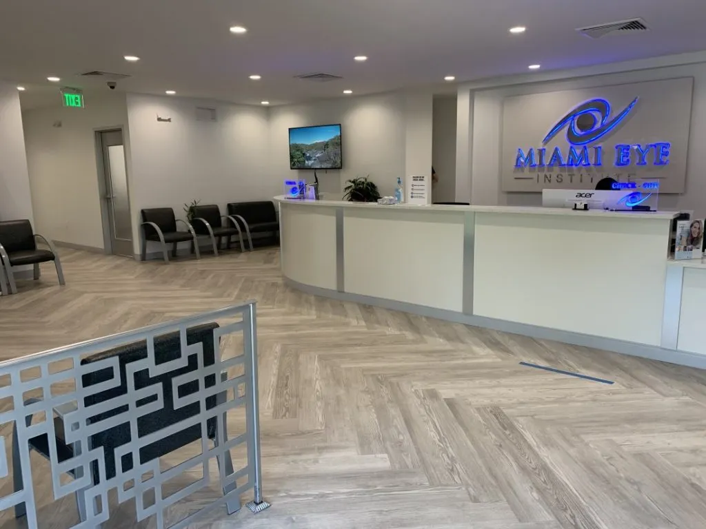 Waiting area chairs and the front desk with the illuminated Miami Eye Institute sign