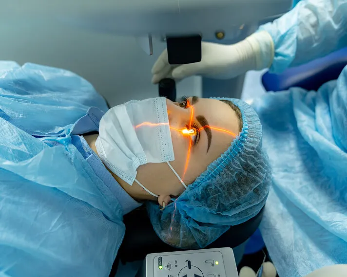 Patient in a surgical cap lying under a laser during an eye procedure